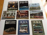 Lot of nine original Buick sales brochures laid out on a white surface. Various model years from 1972 to 1975 represented.