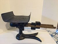 Side profile of the entire postal scale showing the weighing tray, base, and balance beam with sliding weights.