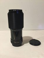 Front side view of Canon zoom lens with Tiffen 58mm Haze filter mounted, lens cap beside it.