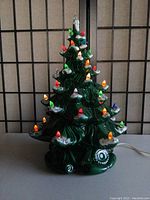 Front view of the ceramic Christmas tree lit with colorful bulbs showing snow tips on branches.