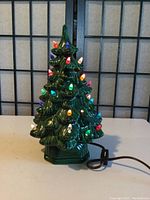 Full front view of the ceramic Christmas tree lit with colorful bulbs in green glaze.