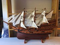 Full side view of the wooden model sailing ship showing multiple sails and wooden hull.