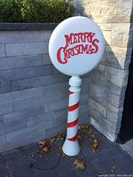 Front view of complete blow mold decoration showing circular sign with red lettering and striped pole.