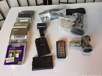 Overview photo showing multiple Cokin filter cases, HOYA UV filter, Marumi remote control, battery adapters, and mounting accessories on a white table surface.