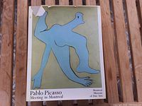 Front cover of the coffee table book showing a stylized blue figure artwork, title and museum name, with some dust cover damage at the top corner.