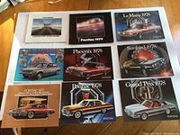 Lot of 9 Pontiac sales brochures laid out on table showing front covers with various 1978 and 1979 Pontiac car models including Le Mans, Phoenix, Sunbird, Catalina, and Grand Prix.