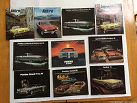Full set of 9 1974 Pontiac sales brochures laid out on a flat surface showing front covers in color featuring multiple Pontiac models including LeMans, Grand Am, Astre, Phoenix, Safari, and others.