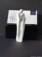 Front view of the white matte Royal Doulton Eternal Love figurine standing in front of the original box showing the full height and form.