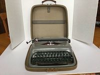 Open tan molded carrying case with grey Tower typewriter inside
