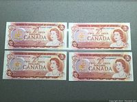 Four 1974 Canadian two dollar bills laid flat showing front sides with Queen Elizabeth II portrait and bilingual denomination.