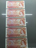 Five consecutive Canadian $2 bills from 1974 stacked together showing consecutive serial numbers.