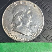 Close-up of the obverse of the 1951 Franklin half dollar coin showing Benjamin Franklin's profile and some wear on the surface.