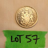 Top side of 1965 Canadian 50 cent coin showing the date, denomination, and Canadian coat of arms. Green tape with Lot 57 marker included.