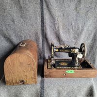 Full view of the Acme vintage sewing machine alongside its wooden curved carrying case with handle.