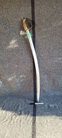 Full length image of the curved saber showing the length and shape of the blade with brass handle and guard.