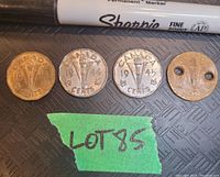Four Canada Victory Nickels laid out with label 'Lot 85'. From left to right: brass 1943 coin, two 1944 chrome plated coins, and a brass coin with holes.