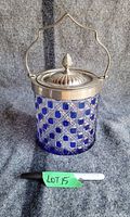 Front view of heavy cut crystal biscuit jar in cobalt blue with silver plated lid and curved handle with figural finial knob