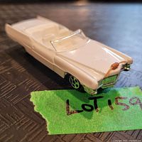 Front and top angled view of the white Cadillac model showing hood, windshield, and front grille with brown detail on hood.