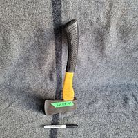 Full view of 15-inch hatchet with yellow handle and black rubber grip, placed on gray carpet with a sharpie pen below for scale.