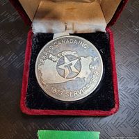 Medal inside red velvet presentation case, showing front side with Canadian map and Texaco star logo, inscribed with dates and company name.