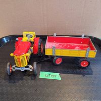 Photo showing the front and side of the tractor and wagon toy set placed on a black tray, highlighting the color and condition.