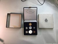 Full view of open presentation box with seven coins and two outer box pieces