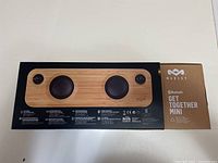 Top view of the packaging showing bamboo wood panel with two main speaker drivers and two smaller circular components, Marley and Bluetooth branding.