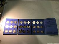 Four blue album holders laid open showing slots with Canadian silver dollars from various years.