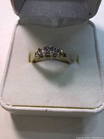 Front view of ring in white presentation box showing three diamonds and prong setting
