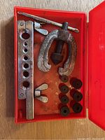 Used double flaring tool kit laid inside an open red plastic case showing the yoke clamp, flaring bar with holes, flaring cone, and multiple adapters.