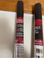 Two rolls of black fiberglass window screen replacement material, labeled Everbilt, size 36in x 84in, shown upright on a wooden surface.
