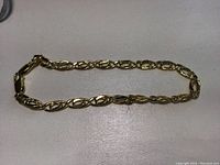 Gold bracelet laid out showing full length of the interlocking oval link chain.