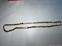 full length of 20-inch gold chain on white surface