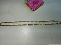 Full view of necklace laid flat on surface with fabric-lined box