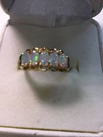 Front view of ring in presentation box showing five opal stones