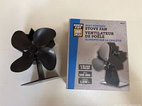 Heat powered stove fan beside its original box showing the product and brand name Power Fist