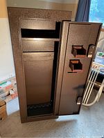 Open front view of upright safe showing interior shelf and base barrel rests
