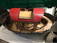 Wooden ship with red cabin roof showing upper deck and lower hull.