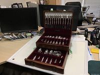 Open wood case showing two drawers with flatware