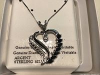 Close-up of the sterling silver heart-shaped pendant necklace by Argent. The pendant displays a combination of genuine sapphires and diamonds, set in sterling silver.