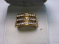 Gold ring with three horizontal diamond rows inside a white box with Tara Vanessa branding.