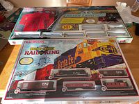 Photo showing opened Silver Lightning HO scale train set box and unopened Rail King E-Z Track System box with detailed artwork and text on packaging.