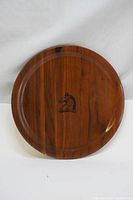Full view of round wooden plate showing walnut grain and central horse head engraving