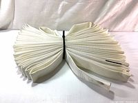 Folded white single jacket fire hose displayed on white surface.