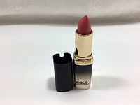 Lipstick with black cap removed and standing upright showing rose gold color bullet and gold gradient case labeled Gold Addiction.