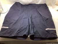 Front view of dark navy FedEx work shorts with cargo pockets and reflective stripes on the legs.