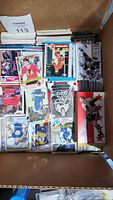 Box of loose sports trading cards laid out showing an assortment of hockey cards including rookies, stars, and insert cards with visible wear.