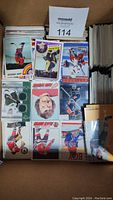 Box of assorted loose hockey trading cards showing a variety of card designs and player inserts.