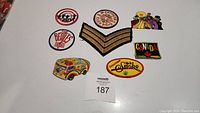 Nine assorted patches including Sgt. stripes, two Beatles patches, psychedelic vans, Cheech and Chong Up in Smoke, Canada patch, and Beatles Help patch arranged on a white surface.