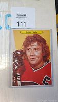 Front of Bobby Clarke OPC hockey card in toploader, showing photo and name.